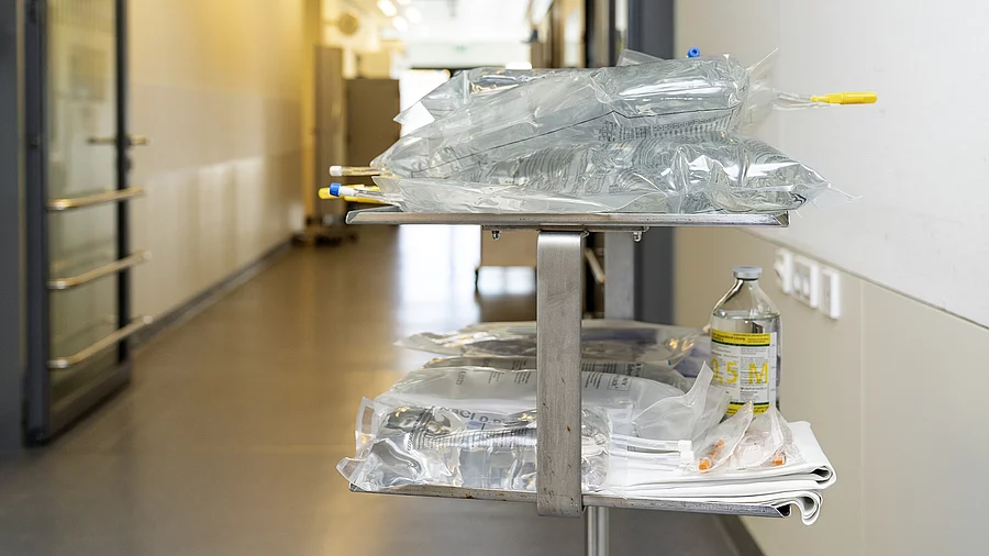 Auf einem Krankenhausflur steht ein Wagen mit mehreren Infusionen.