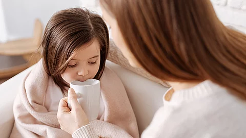 Mutter gibt krankem kleinen Mädchen Tee zu trinken
