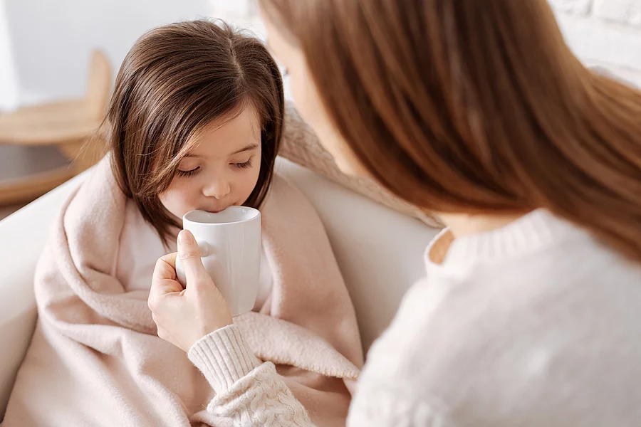 Mutter gibt krankem kleinen Mädchen Tee zu trinken