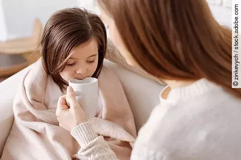 Mutter gibt krankem kleinen Mädchen Tee zu trinken