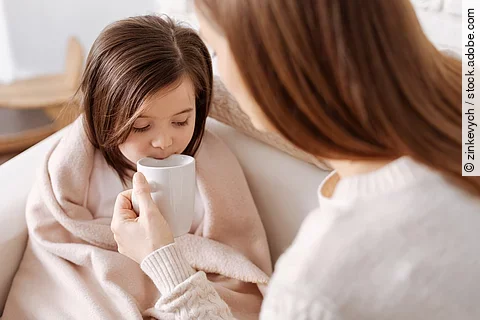 Mutter gibt krankem kleinen Mädchen Tee zu trinken