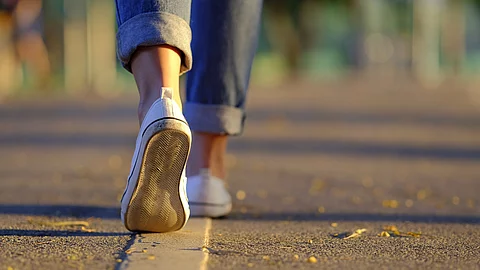 Frauenbeine in Sneakern und Jeans laufen auf der Straße
