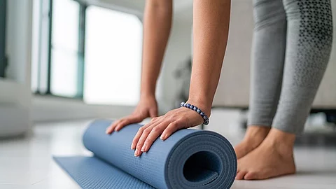Frau rollt ihre Yogamatte zusammen.