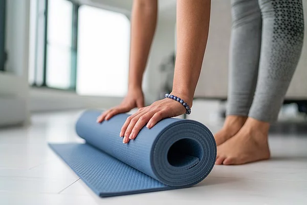 Frau rollt ihre Yogamatte zusammen.