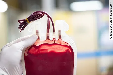 gefüllte Blutkonserve, die von einer Hand mit Handschuh gehalten wird