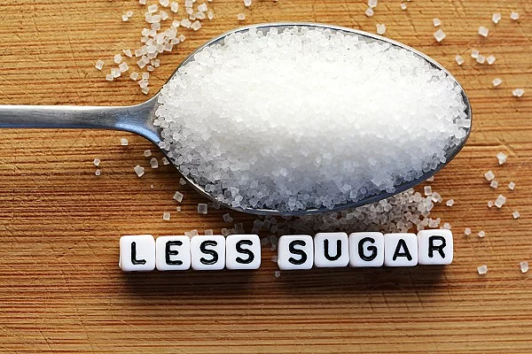 Zucker auf einem Esslöffel mit der Unterschrift Less Sugar.