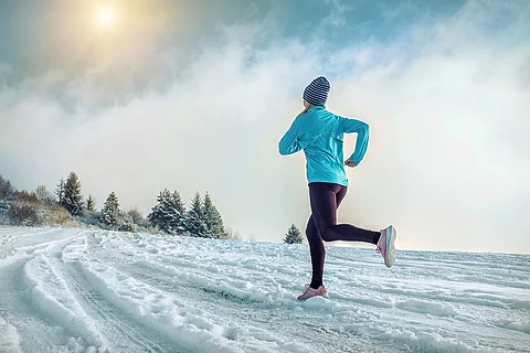 Frau joggt durch Schneelandschaft