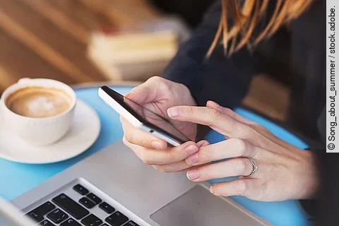 Bildausschnitt mit zwei Frauenhänden, die ein Smartphone halten.