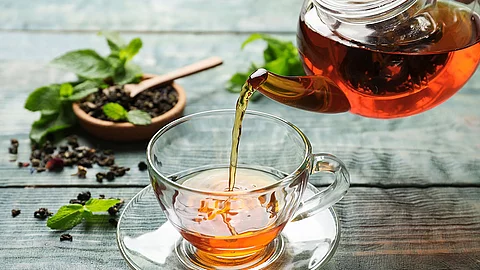 Tee wird aus gläserner Teekanne in gläserne Tasse geschenkt