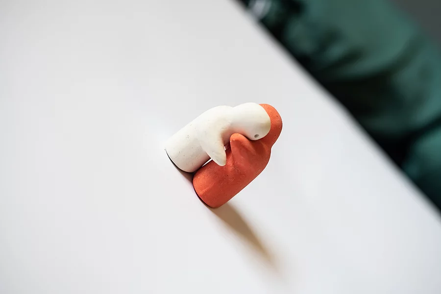 White and orange hug on white. Weiße und orange Figur umarmen sich