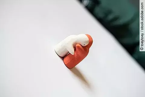 Weiße und orange Figur umarmen sich