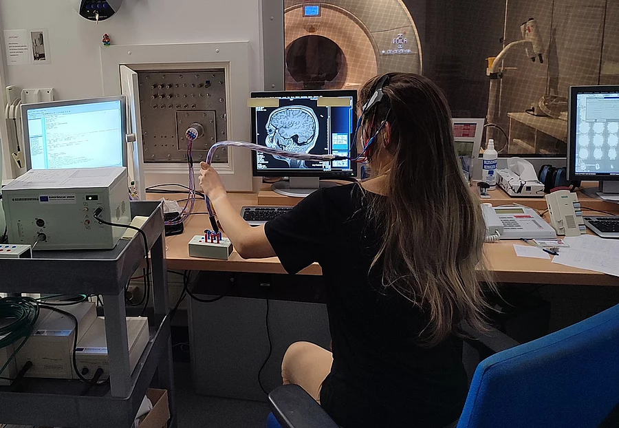 Eine Forscherin sitzt am Rechner und demonstriert das Setup der transkraniellen Gleichstromstimulation