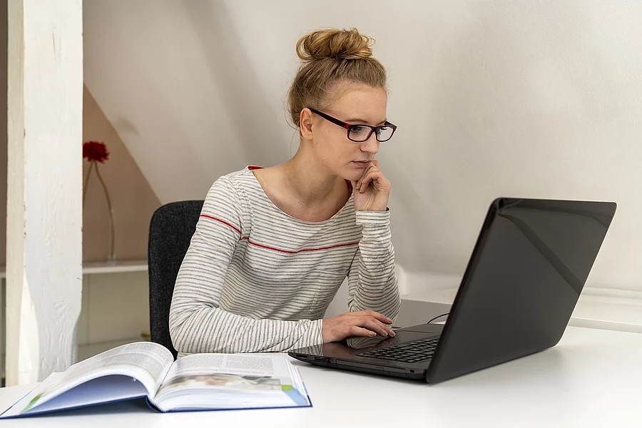 Junge Frau mit Brille liest am Bildschirm