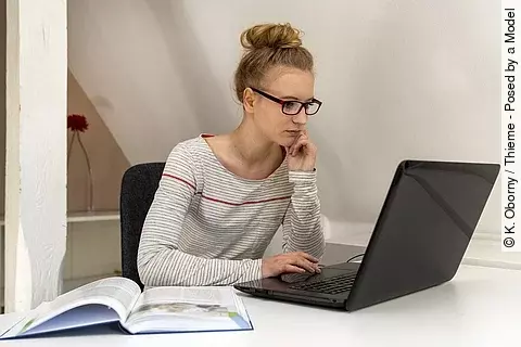 Junge Frau mit Brille liest am Bildschirm