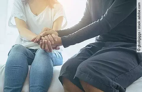 Mann reicht einer Frau seine Hände. 