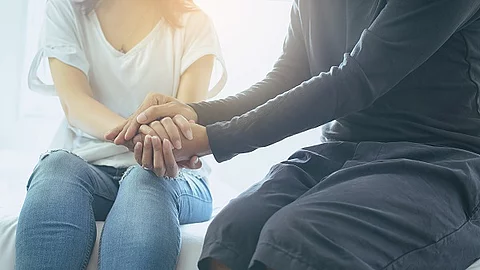 Mann reicht einer Frau seine Hände. 