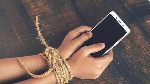 Hands tied by strong rope with mobile Gefesselte Kinderhände mit Smartphone in der Hand; Symbolbild für Handysucht