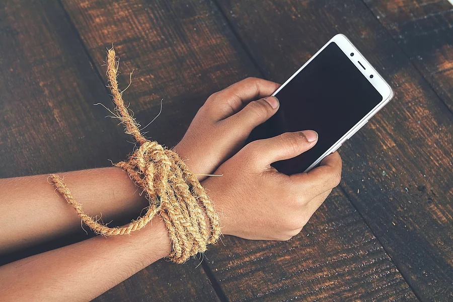 Hands tied by strong rope with mobile Gefesselte Kinderhände mit Smartphone in der Hand; Symbolbild für Handysucht