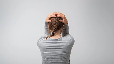 Rückansicht einer Frau, die sich den Kopf hält