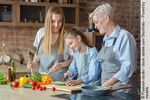 Ältere Frau koch mit ihren Enkeln.