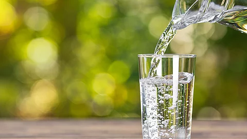 Wasser, das von einer Glaskaraffe in ein Glas geschüttet wird.