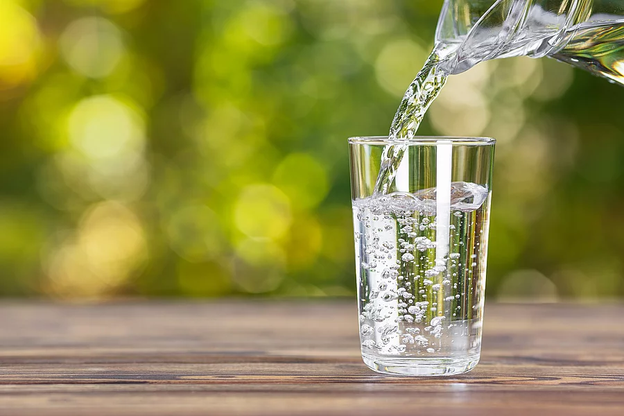 Wasser, das von einer Glaskaraffe in ein Glas geschüttet wird.
