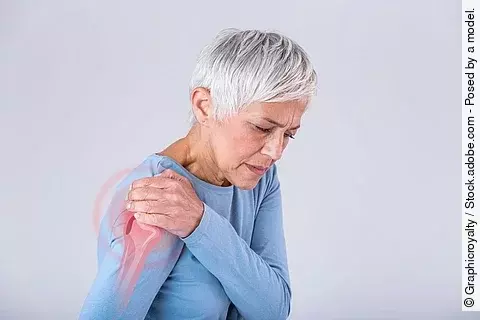 Ältere Frau greift sich an die Schulter