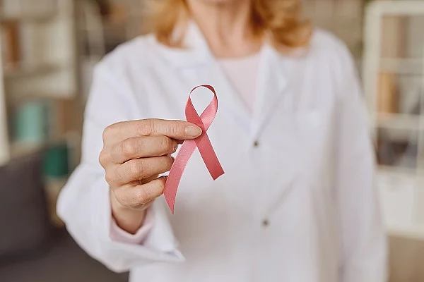 Ärztin hält rosa Schleife für Brustkrebs hoch. 