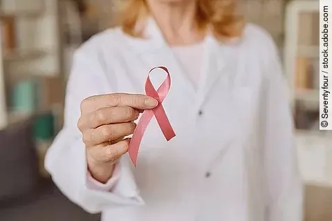 Ärztin hält rosa Schleife für Brustkrebs hoch. 