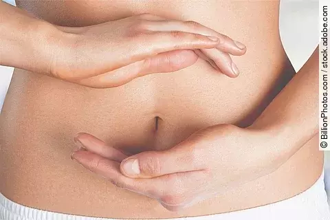 Frau hält ihre beiden Hänge im Kreis um ihren Bauchnabel.