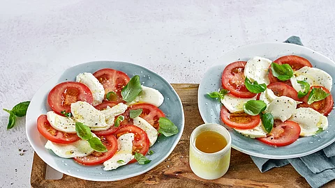 2 Teller mit Tomate, Mozzarella, Basilikum und Olivenöl 2 Teller mit Tomate, Mozzarella, Basilikum und Olivenöl