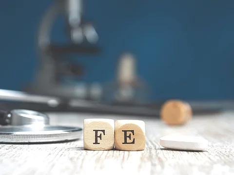 Holzwürfel mit F und E, eine Tablette und ein Stethoskop auf Holzuntergrund