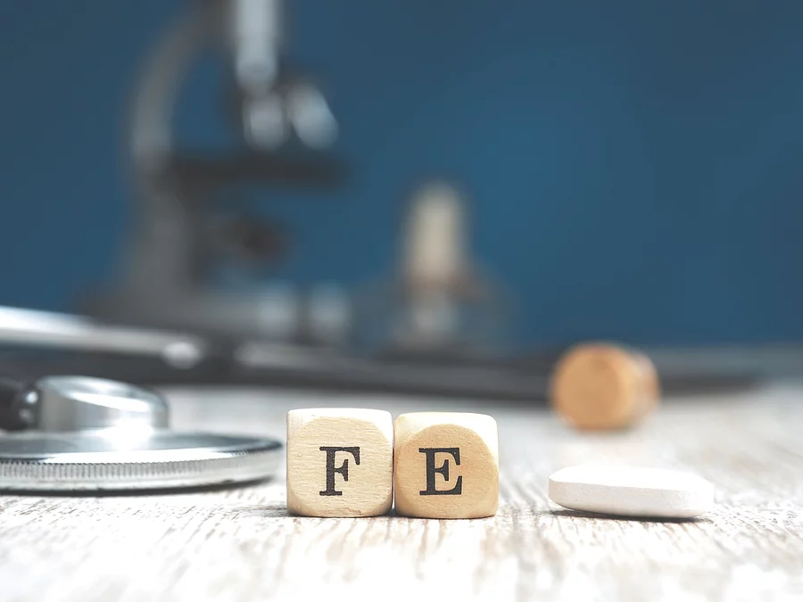 Holzwürfel mit F und E, eine Tablette und ein Stethoskop auf Holzuntergrund