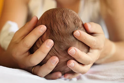 Mutter hält Köpfchen eines Babys