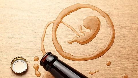 Bierflasche und ein aufgemalter Fötus auf einem Holztisch