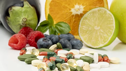 frisches Obst und verschiedene Kapseln/Tabletten