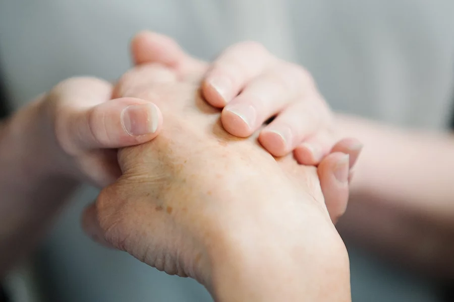 Eine ältere Hand liegt in einer jungen Hand.