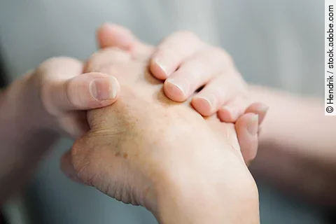 Eine ältere Hand liegt in einer jungen Hand.