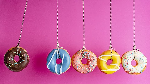 5 Donuts hängen vor pinkfarbener Wand
