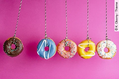 5 Donuts hängen vor pinkfarbener Wand