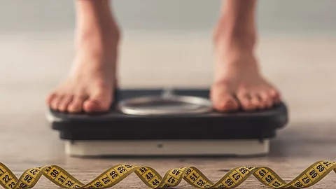 Girl and weight loss Menschliche Füße stehen auf Waage, Maßband liegt daneben