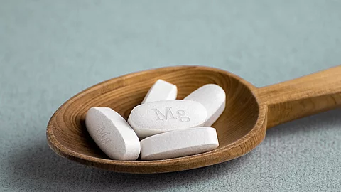 Weiße Tabletten auf einem Holzlöffel