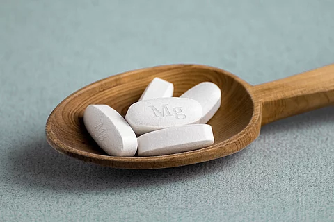 Weiße Tabletten auf einem Holzlöffel