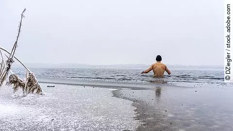Junger Mann mit Mütze geht Eisbaden