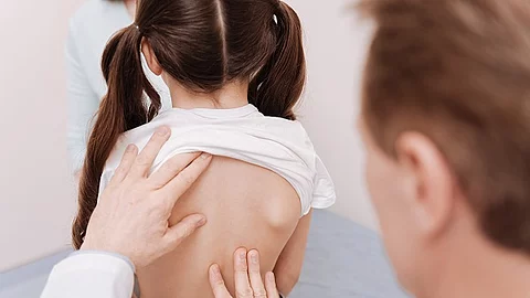 Gentle neat rheumatologist making sure girls spine being healthy Arzt untersucht Mädchen an der Wirbelsäule