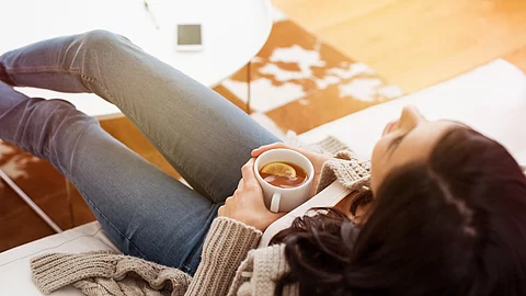 Woman relaxing at home Frau auf dem Sofa mit Tee in der Hand