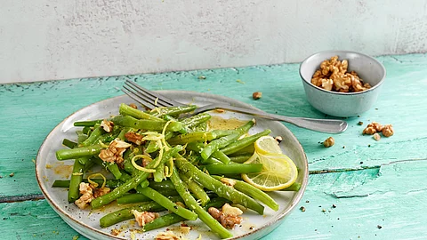Bohnensalat mit Walnüssen und Zitrone attraktiv komponiert auf türkisem Holzuntergrund