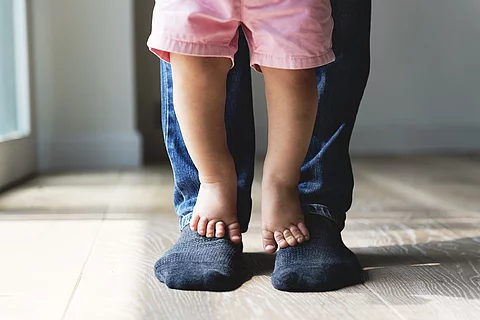 Kind steht auf Füßen des Vaters 