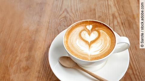 Eine Tasse Cappuccino auf Holztisch.