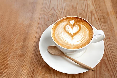 Eine Tasse Cappuccino auf Holztisch.